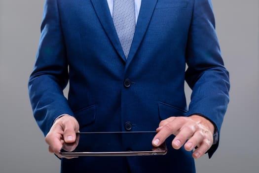 Midsection of caucasian businessman using tablet, isolated on grey background. business technology, communication and growth concept.