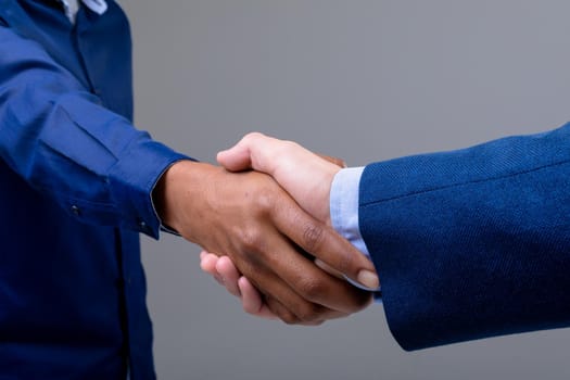 Caucasian and african american business people shaking hands, isolated on grey background. business technology, communication and growth concept.