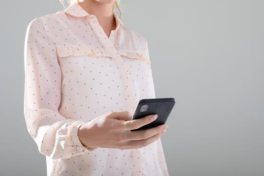 Midsection of caucasian businesswoman using smartphone, isolated on grey background. business, technology, communication and growth concept.