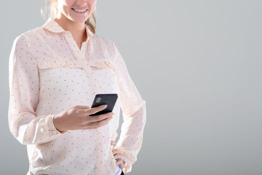 Smiling caucasian businesswoman using smartphone, isolated on grey background. business, technology, communication and growth concept.