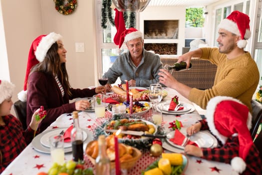 Caucasian multi generation family wearing santa hats having christmas meal. family christmas time and festivity together at home.