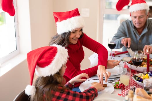 Caucasian multi generation family wearing santa hats having christmas meal. family christmas time and festivity together at home.