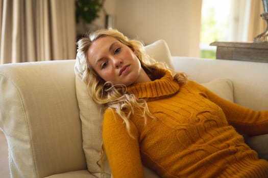 Portrait of thoughtful caucasian woman lying back on couch relaxing n luxury living room. spending free time at home.