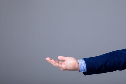 Midsection of caucasian businessman reaching his hand, isolated on grey background. business technology, communication and growth concept.