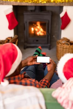 Back view of african american senior couple using smartphone with copy space at christmas time. retirement lifestyle and christmas festivities, celebrating at home.