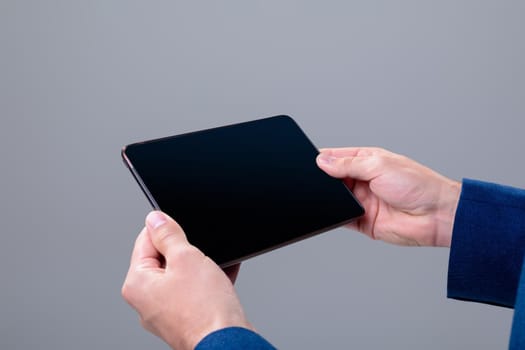 Midsection of caucasian businessman using tablet, isolated on grey background. business technology, communication and growth concept.