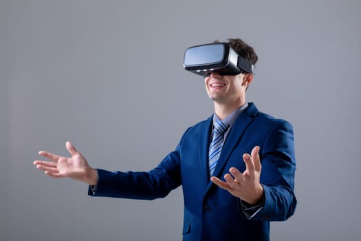 Caucasian businessman wearing vr headset widening his arms, isolated on grey background. business technology, communication and growth concept digitally generated composite image.