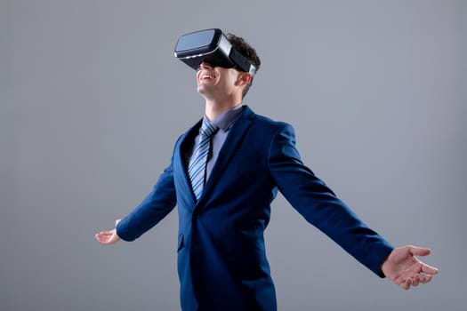 Caucasian businessman wearing vr headset widening his arms, isolated on grey background. business technology, communication and growth concept digitally generated composite image.