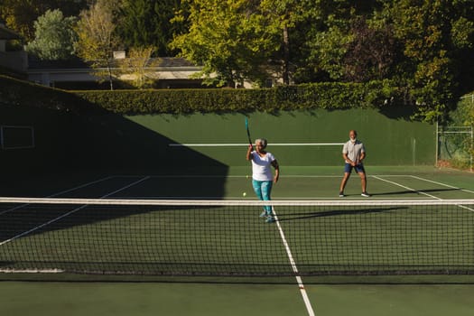 Senior african american couple playing tennis on tennis court. retirement and active senior lifestyle concept.