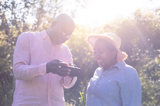 Happy african american senior couple taking selfie outdoors. retirement lifestyle, spending time at home and garden.