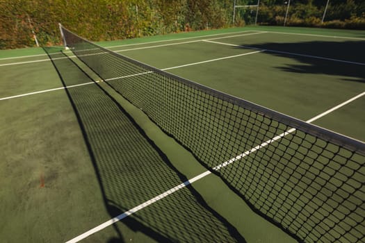 General view of tennis court and tennis net on sunny day. retreat, leisure time facilities and active lifestyle concept.