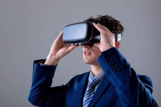 Caucasian businessman wearing vr headset, isolated on grey background. business technology, communication and growth concept digitally generated composite image.