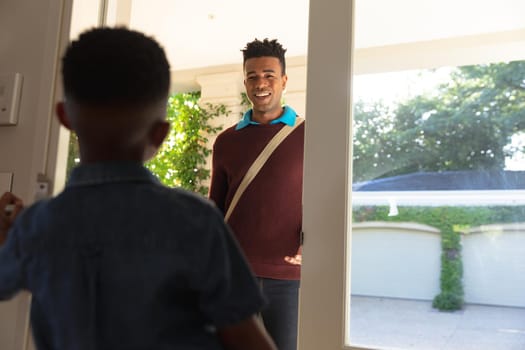 Happy african american father with son back from work smiling at home. family enjoying quality free time together.