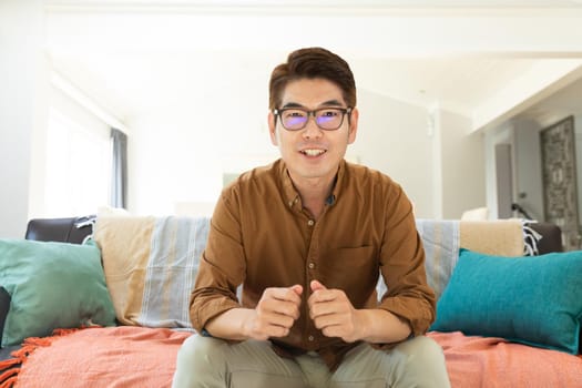 Asian man smiling during video call at home. domestic lifestyle and working online during covid 19 pandemic concept.