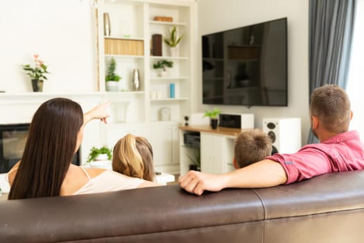 Caucasian couple with son and daughter sitting on couch watching television at home. domestic lifestyle and leisure family time concept.