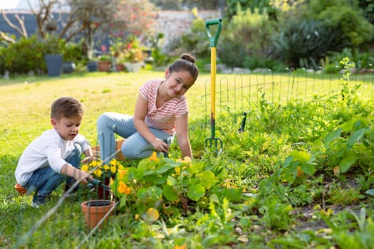 Happy caucasian sister and brother gardening together. family time, having fun together at home and garden.