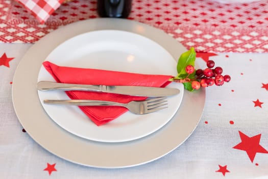 Plates with cutlery, holy and decorations on christmas table. christmas, festivity and tradition at home.