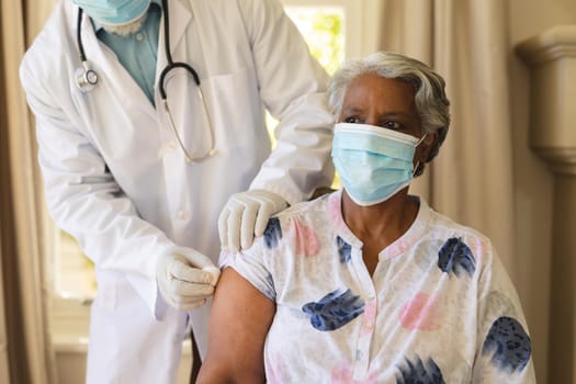 Senior african american woman in face mask receiving vaccination. retirement and senior lifestyle during covid 19 pandemic concept.