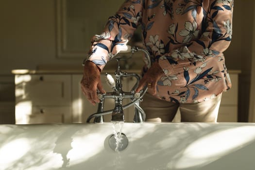 Senior caucasian woman running a bath in bathroom. retreat, retirement and happy senior lifestyle concept.