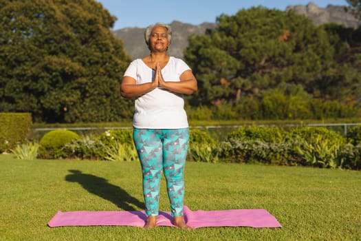 Senior african american woman with eyes closed practicing yoga in stunning countryside. retirement and active senior lifestyle concept.