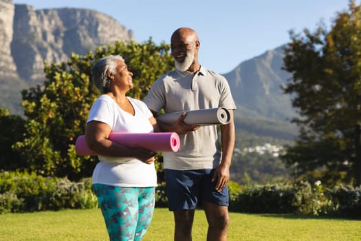 Portrait of smiling senior african american couple with yoga mat in countryside retreat. retirement and active senior lifestyle concept.
