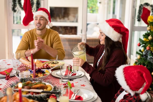 Caucasian family wearing santa hats having christmas meal. family christmas time and festivity together at home.