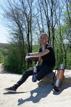 a man on a prosthetic leg travels the mountains. Dressed in black jeans and a T-shirt. sitting on a stone