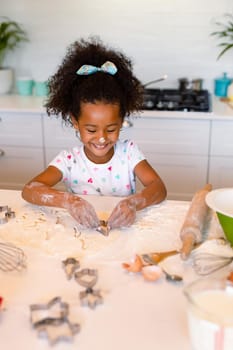 Happy african american messy girl baking in kitchen. baking and cooking, childhood and leisure time at home.