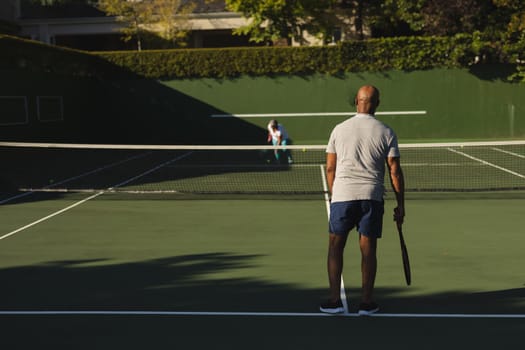 Senior african american couple playing tennis on tennis court. retirement and active senior lifestyle concept.