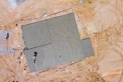 Construction worker using machine application grinding cement screed foundation on new house complex of construction site