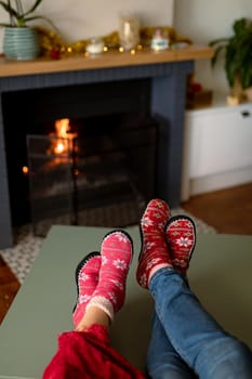 Feet of caucasian couple wearing christmas socks at christmas time. family christmas time and festivity together at home.