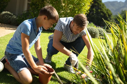 Happy caucasian father and son outdoors, gardening on sunny day. family enjoying quality free time together.