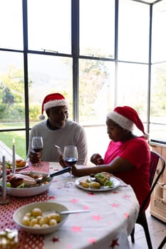 African american senior couple in santa hats using smartphone at christmas time. retirement lifestyle, christmas festivities and communication technology.