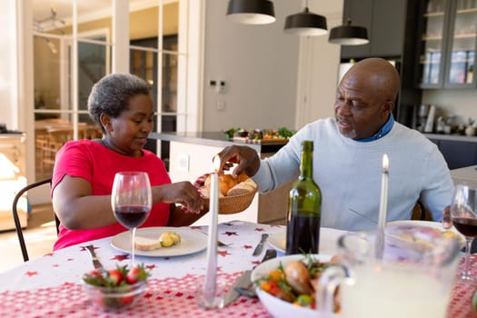 Happy african american senior couple having christmas meal at home. retirement lifestyle and christmas festivities, celebrating at home.