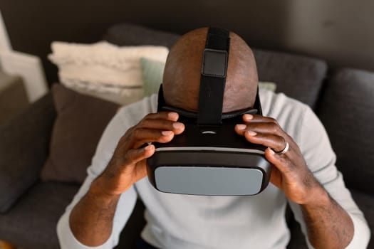 African american senior man wearing vr headset and having fun at home. retirement lifestyle, technology and spending time at home.
