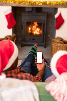 Back view of african american senior couple using smartphone with copy space at christmas time. retirement lifestyle and christmas festivities, celebrating at home.
