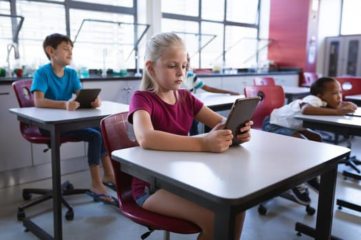 Caucasian girl using digital tablet while sitting on her desk in the class at school. school and education concept