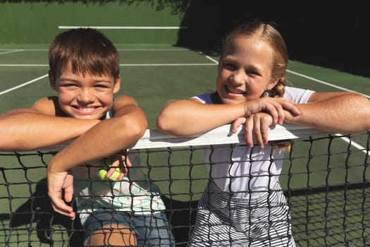 Portrait of caucasian boy and girl outdoors, smiling on tennis court. family enjoying healthy free time activities together.