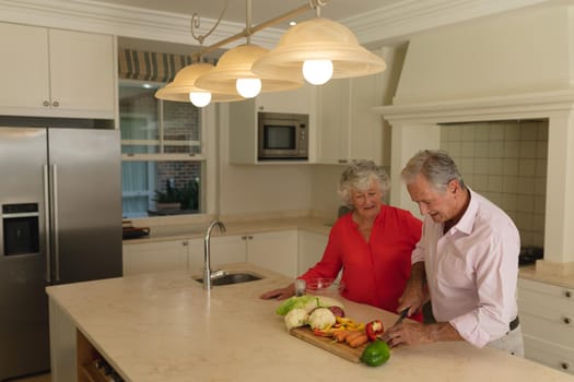 Senior caucasian couple cooking together and talking in kitchen. retreat, retirement and happy senior lifestyle concept.