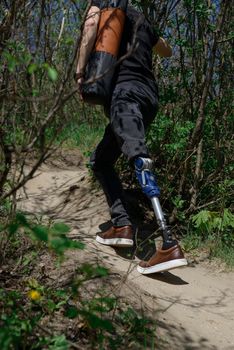 a man on a prosthetic leg travels the mountains. Dressed in black jeans and a T-shirt, he carrying mat.