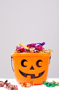 Composition of halloween bucket with trick or treat sweets on white background. halloween tradition and celebration concept.