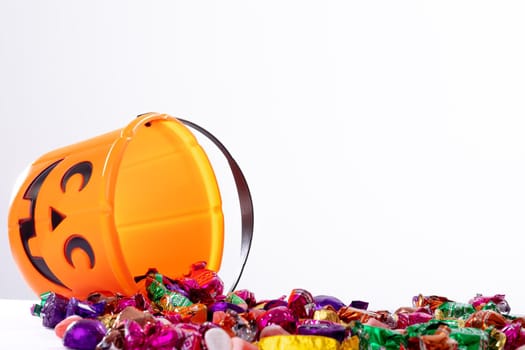 Composition of halloween bucket with trick or treat sweets on white background. halloween tradition and celebration concept.