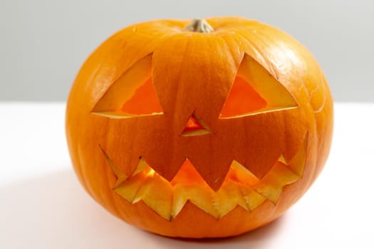 Composition of scary halloween carved orange pumpkin on white background. halloween tradition and celebration concept.
