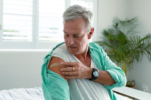 Caucasian senior man with plaster on arm after vaccination. senior health and lifestyle during covid 19 pandemic.