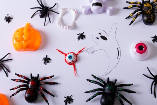 Composition of halloween decorations with spiders, ghost and pumpkin on white background. halloween tradition and celebration concept.