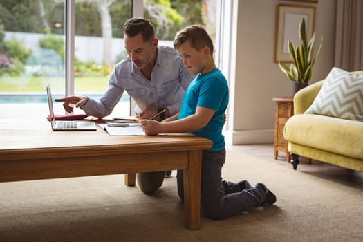 Caucasian father using laptop to help his son with homework at home. home schooling and education concept