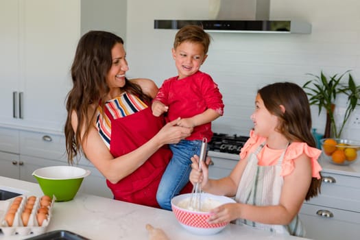 Happy caucasian mother, daughter and son baking together, making cookies in kitchen. family time, having fun together at home.