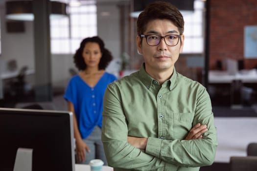 Portrait of serious asian businessman standing in office with female colleague in background. working in business at a modern office.