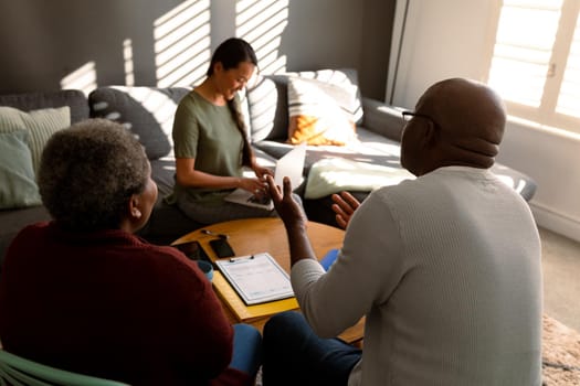 African american senior couple having meeting with asian female financial advisor at home. retirement lifestyle, elderly support and spending time at home.