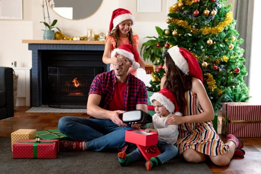 Happy caucasian family wearing santa hat, unpacking presents at christmas time. family christmas time and festivity together at home.
